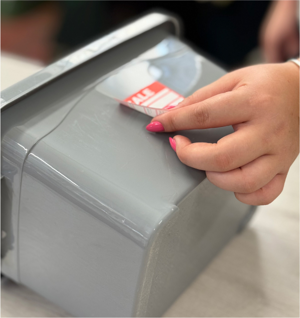 A hand peeling a label cleanly from a surface, showcasing adhesive quality.